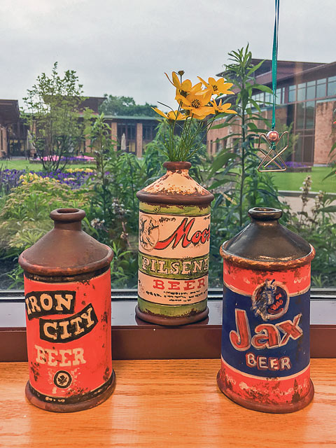 Three ceramic beer cans on a windowsill