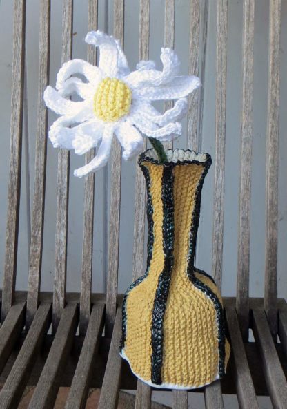 yellow black vase with knitted daisy